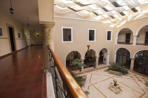 A spacious interior with a high ceiling, arched columns, and a central courtyard with seating and plants. - Experience Mérida Your Way | Comfortable Stay + Pool (Mérida)