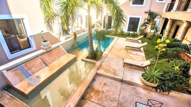 A pool area with a hot tub, lounge chairs, and palm trees. - Experience Mérida Your Way | Comfortable Stay + Pool (Mérida)