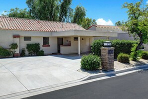 A two-story building with a tiled roof, a front entrance, and a driveway leading to a parking area. - Relaxing 2 Bedroom Palm Resort Escape (Palm Desert)