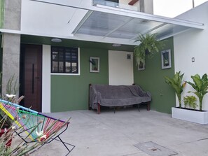 Un espacio al aire libre techado con un sofá, una hamaca y plantas en macetas.