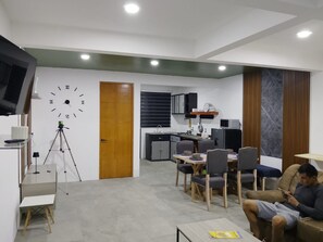 Un espacio habitable moderno con comedor, cocina y televisor montado en la pared.