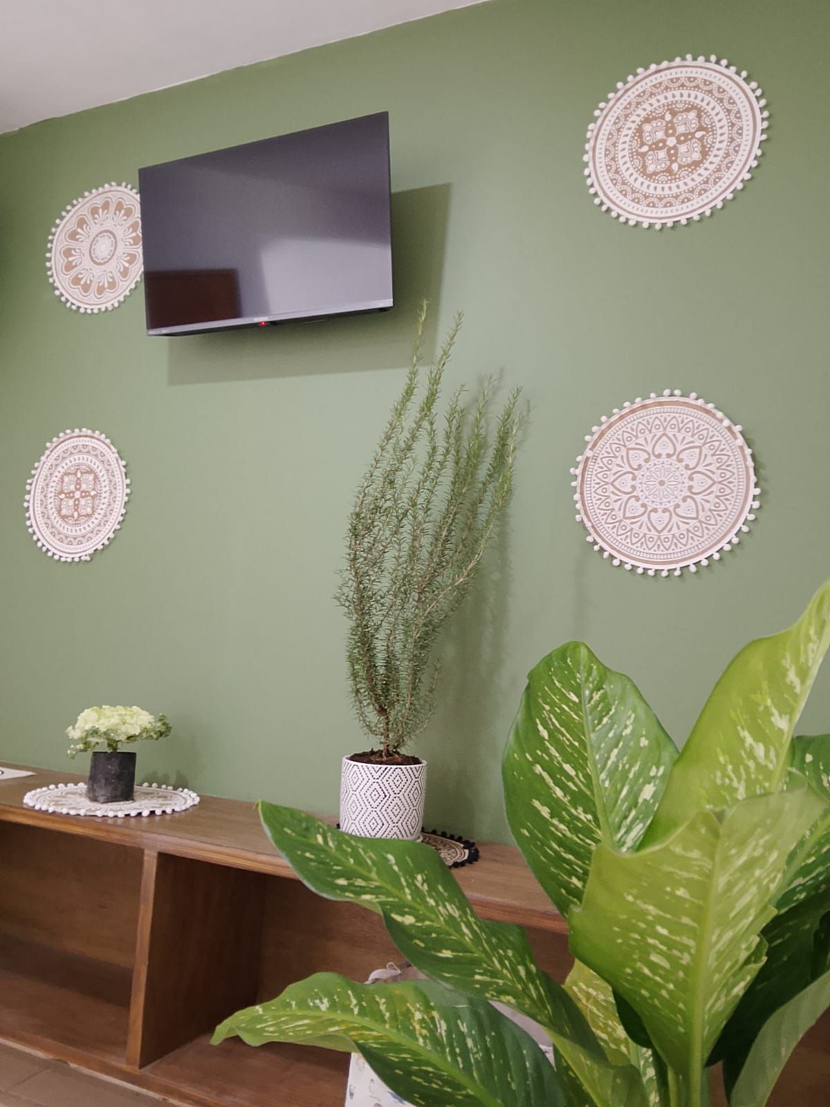 Une pièce dotée d’un téléviseur à écran plat fixé sur un mur vert, le tout agrémenté de décorations murales.