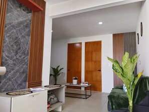 A modern interior with a reception desk, a plant, and a wooden door in the background.