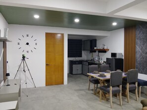 A modern kitchen with dark cabinets, a wooden door, and a dining area with a table and chairs.