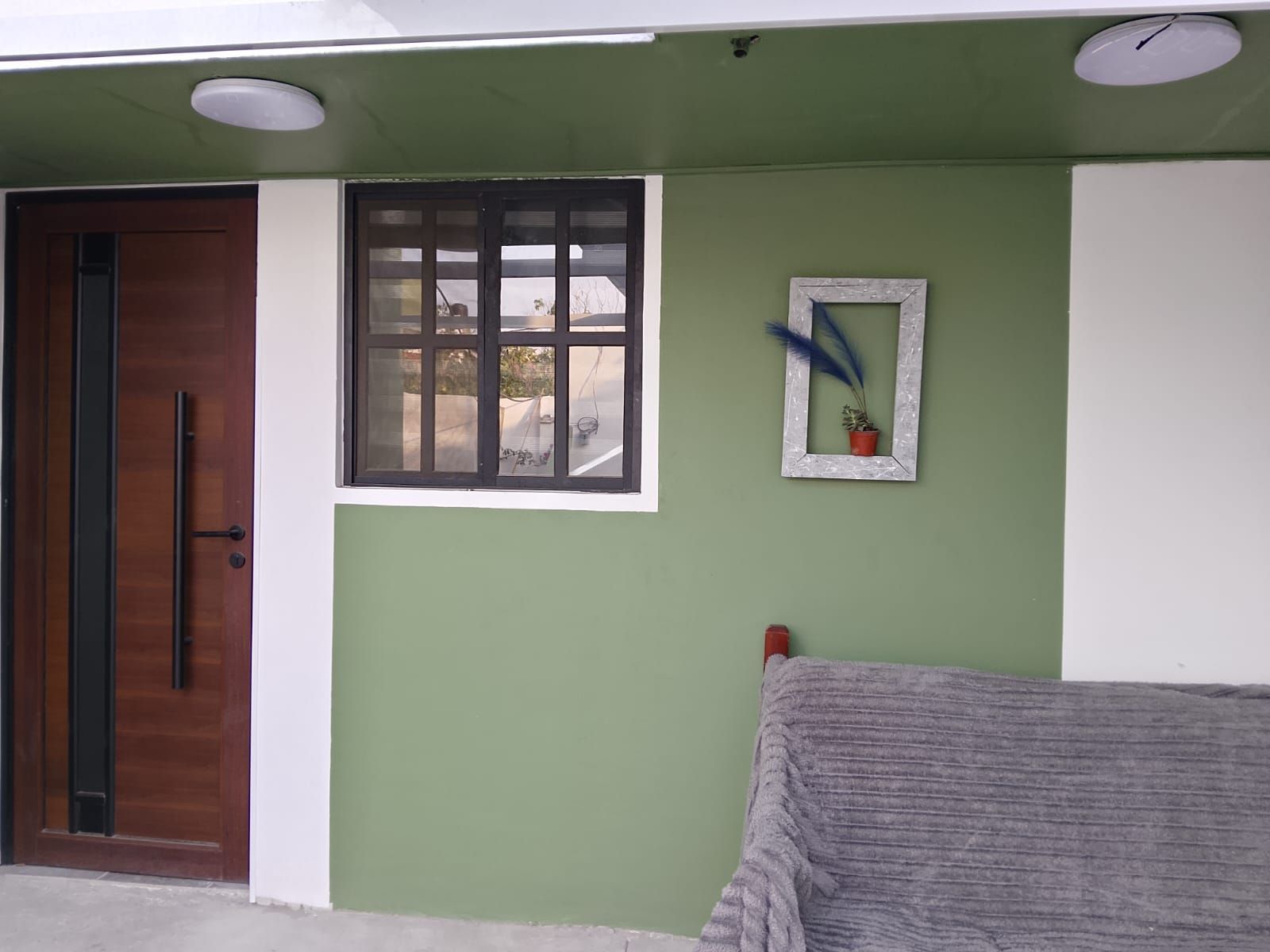 Une pièce avec une porte en bois, une fenêtre donnant sur un beau paysage et un petit tableau encadré accroché au mur.