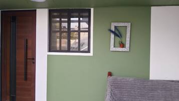 Une pièce avec une porte en bois, une fenêtre donnant sur un beau paysage et un petit tableau encadré accroché au mur.