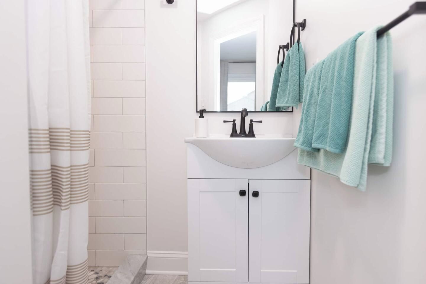 Un bagno con lavandino bianco, uno specchio e un portaservizi con asciugamani.