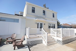 A two-story house with a front porch, a small deck, and a garage. - Wildwood Crest Beach House | 4BR, Sleeps 9 (Wildwood Crest)