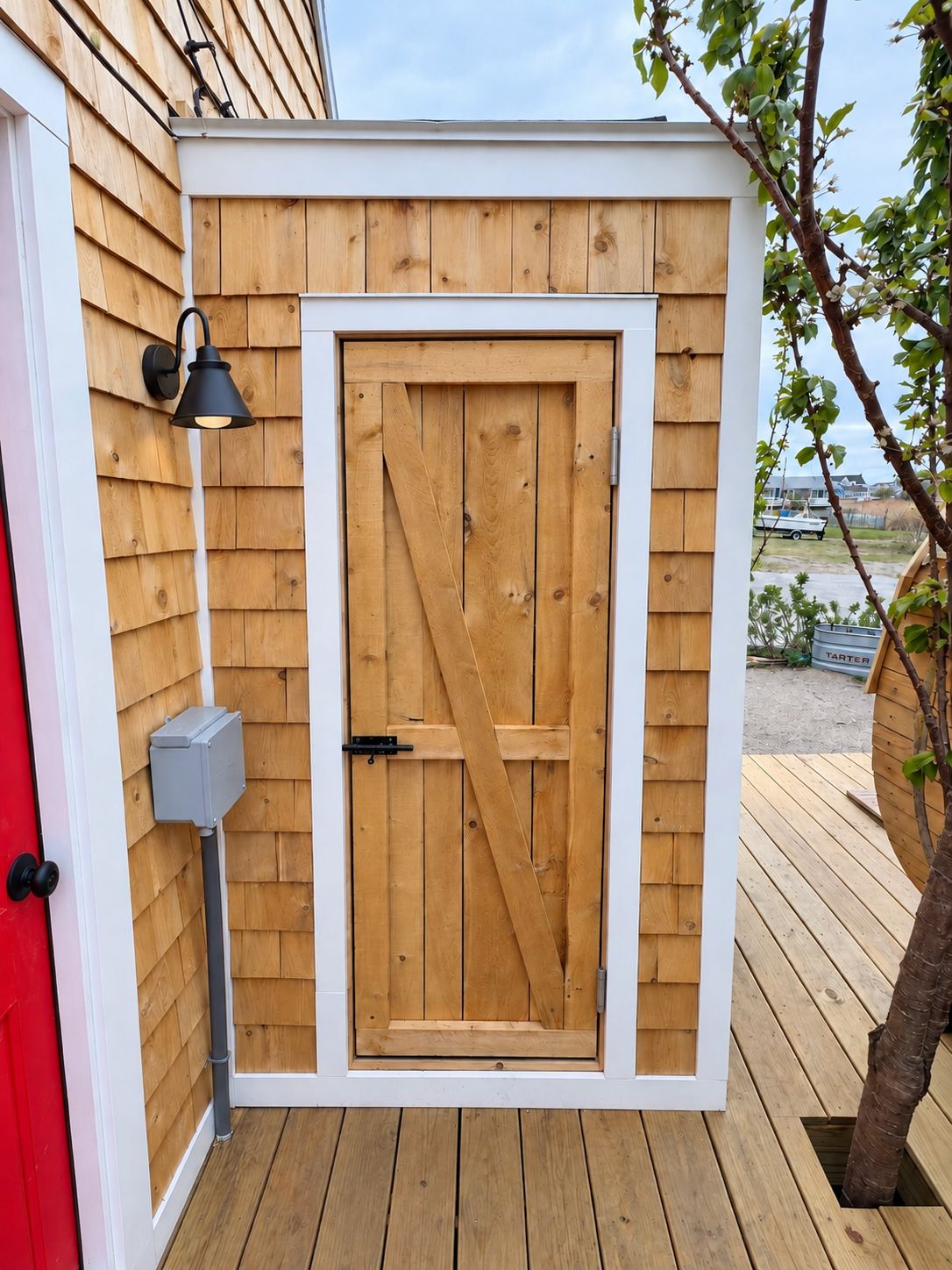 A wooden shed with a white door and a black exterior light fixture.