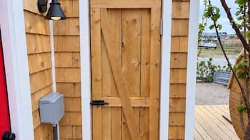 A wooden shed with a white door and a black exterior light fixture.