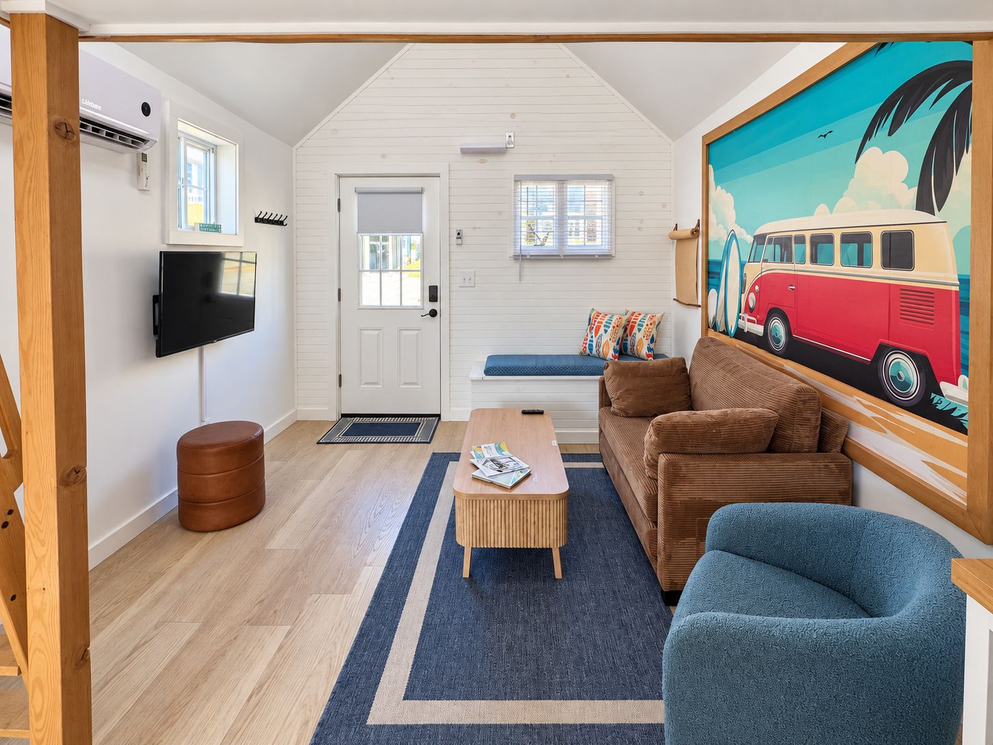 A cozy living room with a sofa, a coffee table, a TV, and a painting of a van.
