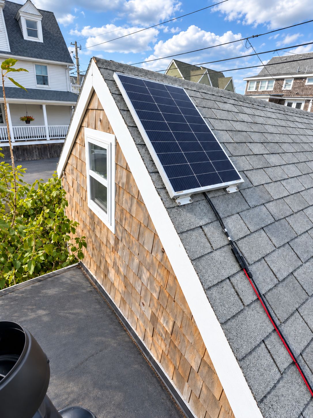 A residential building with a sloped roof, a solar panel, and a small window.