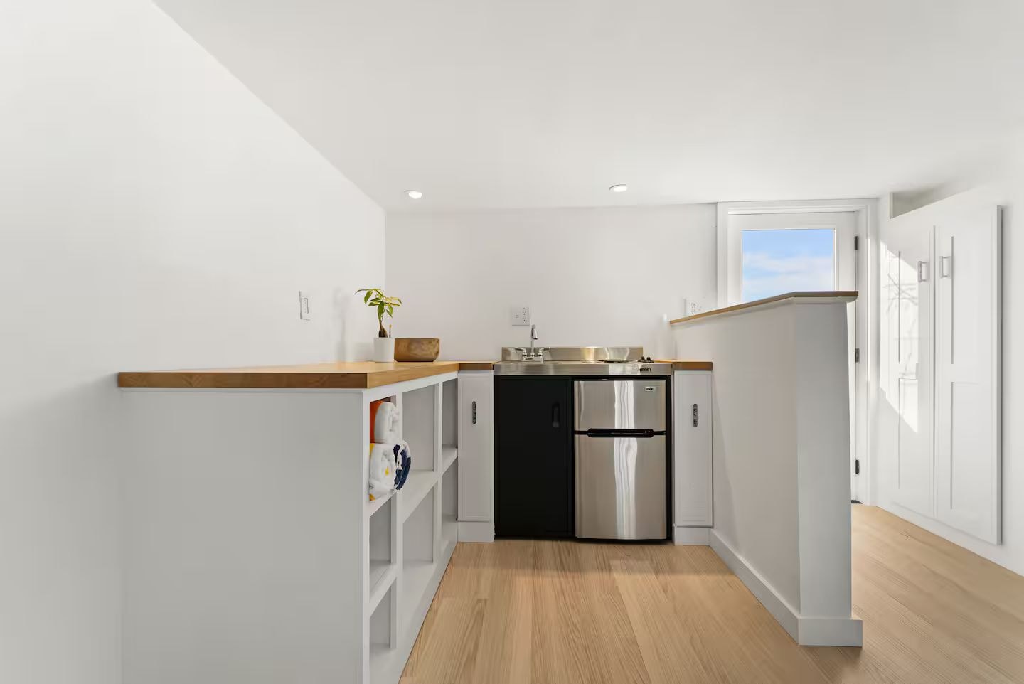 Eine moderne Küche mit weißen Schränken, einem Edelstahlkühlschrank und einer Holz Arbeitsplatte.
