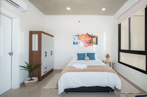 A bedroom with a bed, a wardrobe, a bedside table, a lamp, and a window. - Zuba IV Studio | Rooftop Pool & WiFi (Luque)
