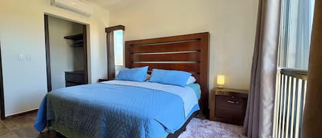 A bedroom with a bed, a nightstand, a ceiling fan, and a window with curtains.