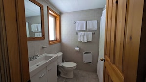 A bathroom with a toilet, sink, and mirror. - L'Ours Bleu (Lac-Saguay)