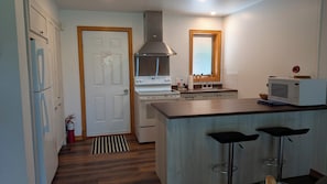 Una cocina moderna con estufa, microondas y taburetes de bar.