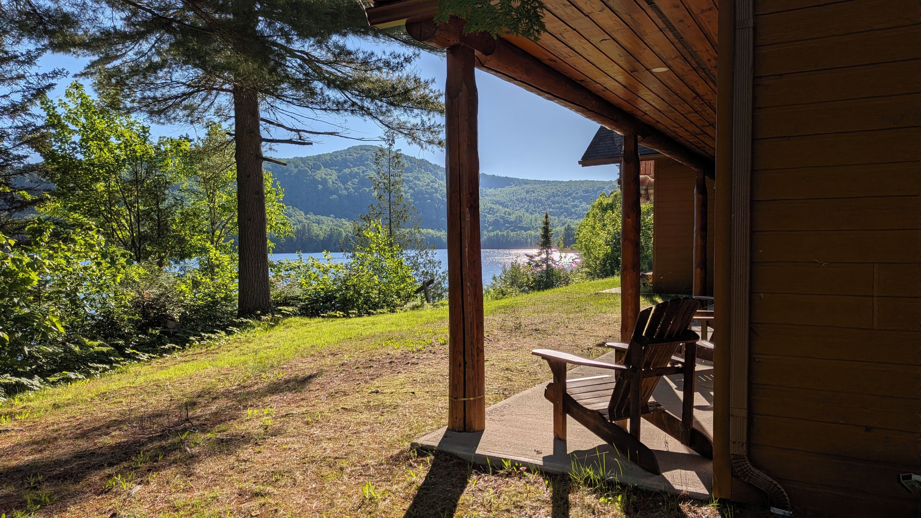 Une structure en bois comprenant un banc et une table, offrant une vue sur un lac et des collines boisées.