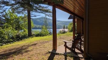 Une structure en bois comprenant un banc et une table, offrant une vue sur un lac et des collines boisées.