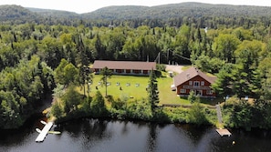 A lodge with a large deck area, a dock, and a forested backdrop.