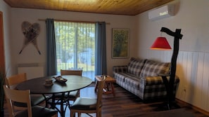 A cozy living room with a round table, plaid sofa, and a red floor lamp. - L'Ours Bleu (Lac-Saguay)