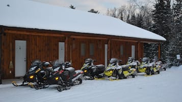 Una filera de motos de neu estacionades davant d'un edifici de fusta amb portes numerades.