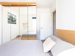 A bedroom with a bed, a wooden headboard, a wall-mounted picture, and a door leading to another room. - CHL Casa Arthur, El Médano beach penthouse (El Médano)