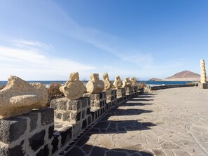 A stone pathway leading to a coastal area with a view of the sea and a mountain in the distance. - CHL Casa Arthur, El Médano beach penthouse (El Médano)