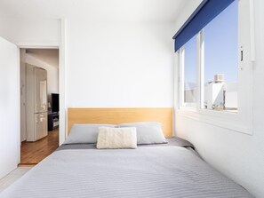 Una camera da letto con un letto, una testata in legno e una finestra vista edifici.