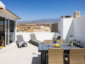 Una terrazza sul tetto con arredi da esterno, un tavolo da pranzo e vista su un paesaggio desertico.