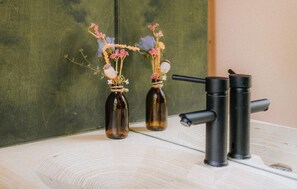 Two brown glass bottles with flowers and a black faucet.