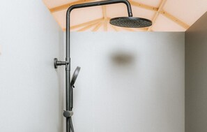 A shower with a handheld showerhead and a wall-mounted control.