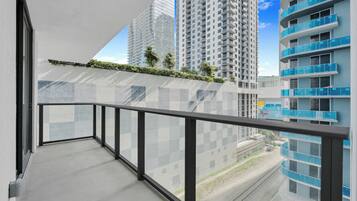 A balcony with a view of high-rise buildings and a railway track.
