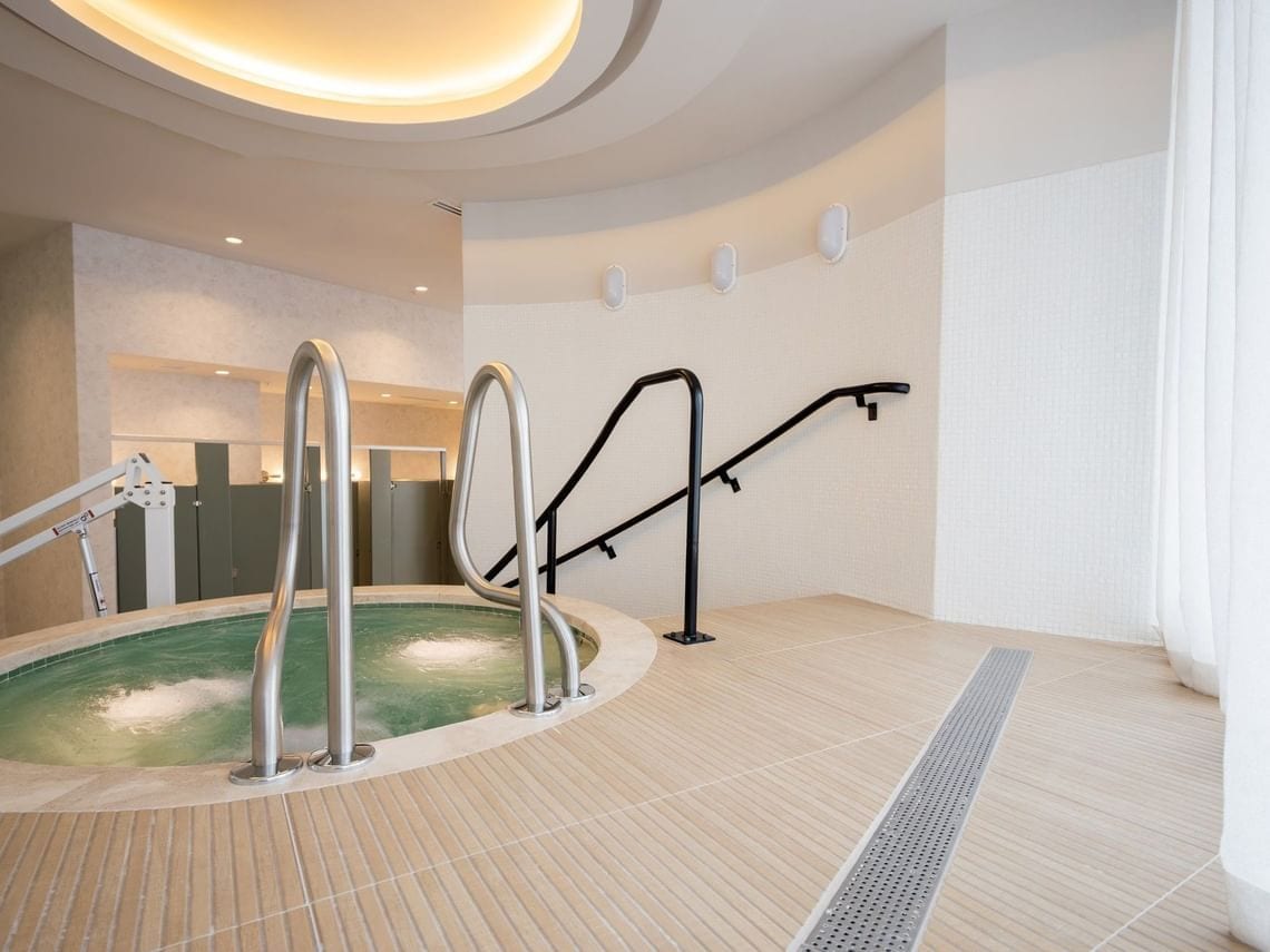 A spa area with a hot tub, metal steps, and a towel rack.
