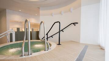 A spa area with a hot tub, metal steps, and a towel rack.