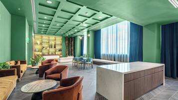A modern lobby with a reception desk, seating area, and a decorative bookshelf.