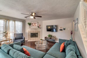 Ein Wohnzimmer mit Kamin, Deckenventilator, Flachbildfernseher und einer Couch.