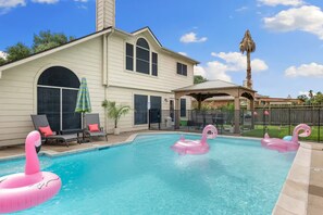 Ein Garten mit Schwimmbad, Liegestühlen und Flamingo-Schwimmgeflügeln.