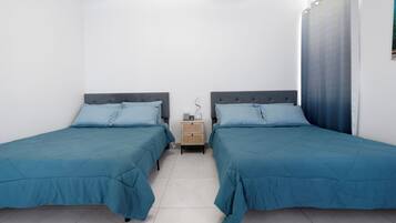 A twin room with two beds, a nightstand, and a window with curtains.