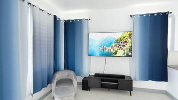 A modern living room with a flat-screen TV mounted on the wall, a grey sofa, and a black entertainment unit.