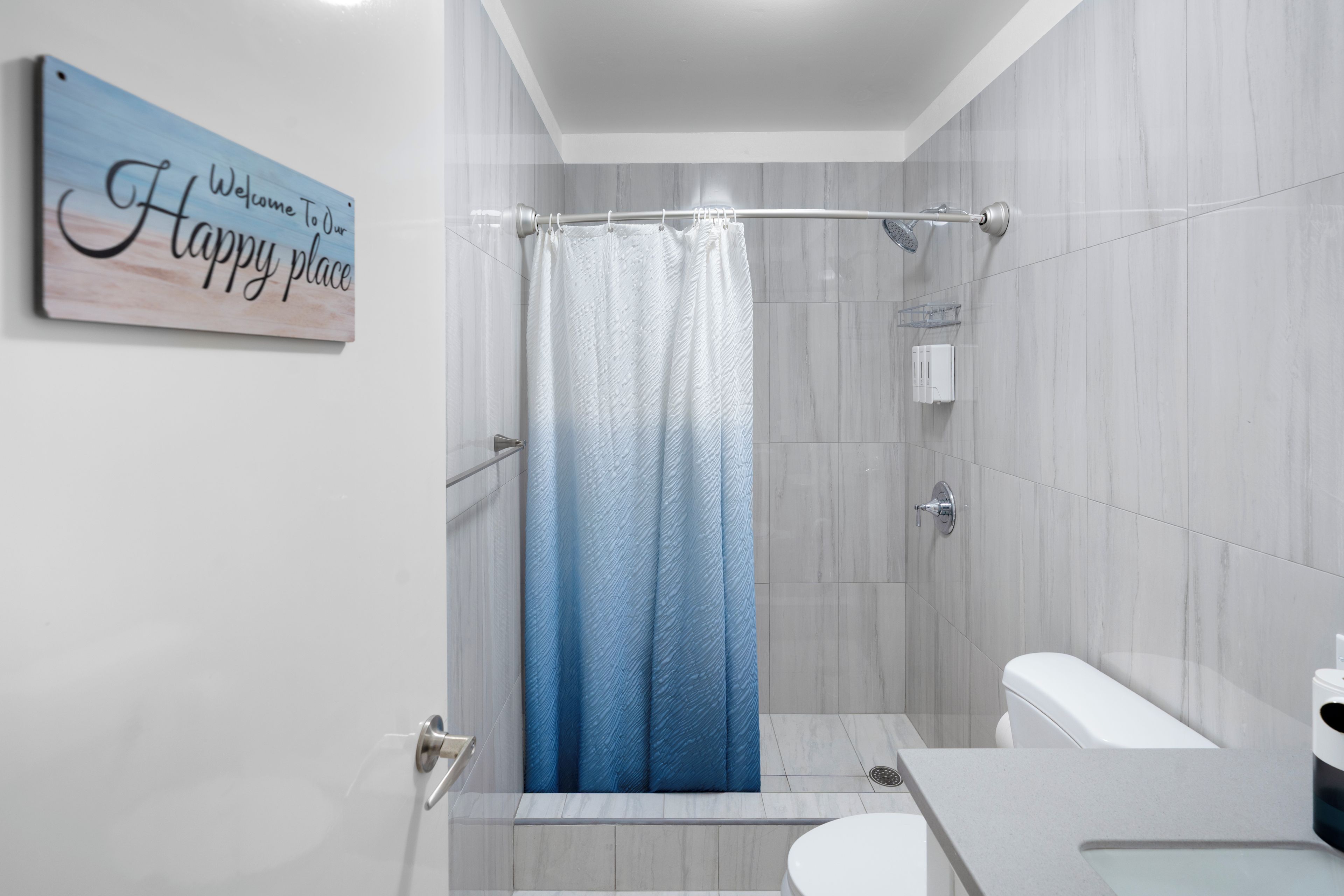 Une salle de bain moderne équipée d’un rideau de douche, de toilettes et d’un sèche-mains.