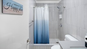 Un baño moderno con cortina de ducha, inodoro y secador de manos.