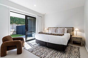 Ein Schlafzimmer mit einem großen Bett, zwei Nachttischlampen, einem kleinen Tisch und einem Sessel.