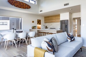 A modern living space with a dining area, kitchen, and a sofa with decorative pillows. - 3 x Townhouses • Central • Modern (Raglan)