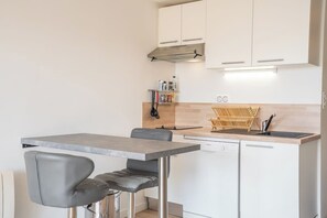 Cozinha compacta com área de refeições, equipada com lava-louças, bancada de madeira e exaustor embutido.