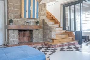 Ein Kamin aus Stein mit einer hölzernen Wendeltreppe, die zu einem Balkon führt.