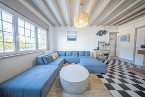 Ein Wohnzimmer mit einem Ecksofa, einem runden Couchtisch und einem Schachbrettmuster-Boden.