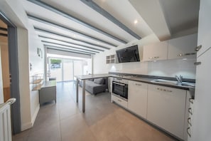 Eine moderne Küche mit eingebautem Ofen, einem Essbereich mit Tisch und einem großen Fenster, das für natürliches Licht sorgt.