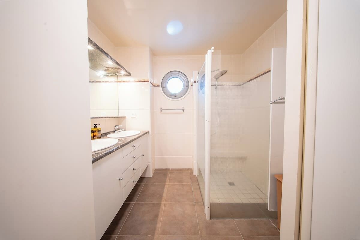 Ein Badezimmer mit Dusche, Waschbecken und Spiegel.