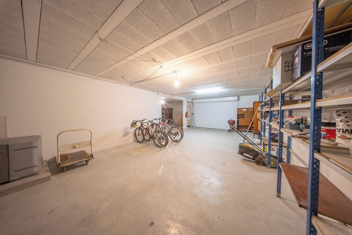 A garage with bicycles, a cart, and shelves with boxes.